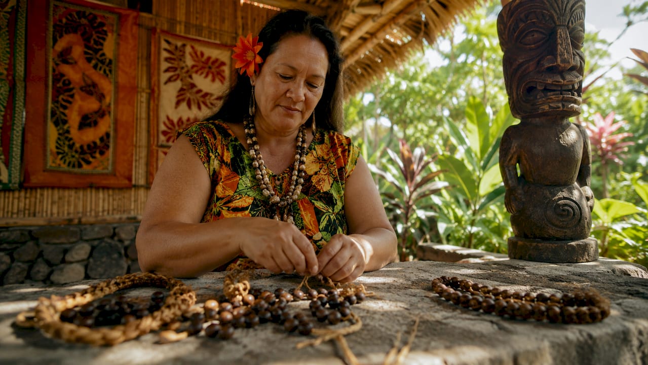 Native Hawaiian woman arranging traditional leis indoors