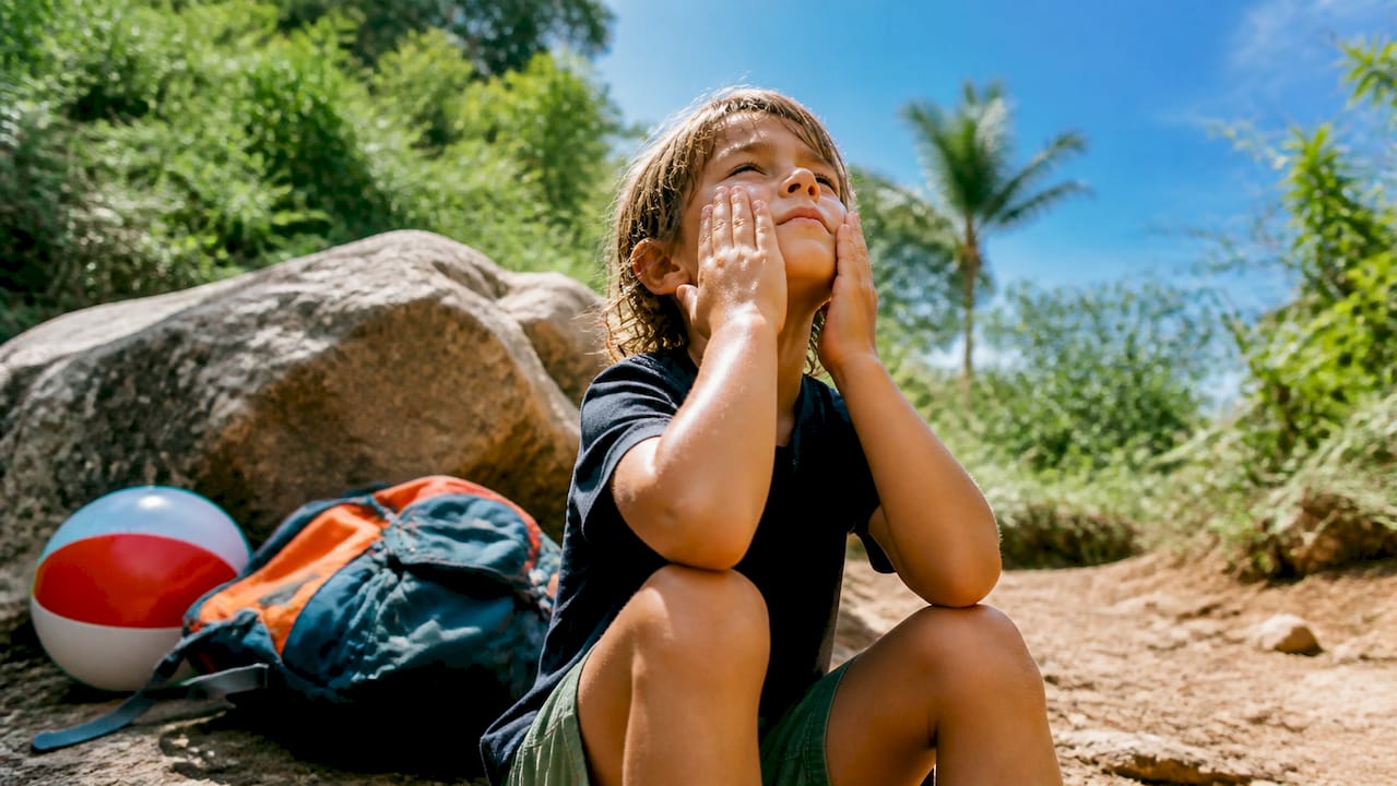 Child applying sunscreen on hiking trail