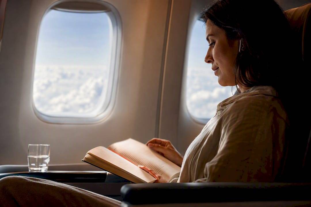 Traveler reading beside airplane window