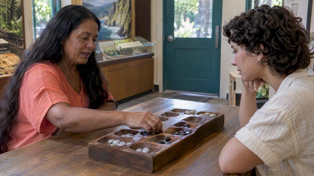 Cultural practitioner demonstrating kōnane to visitor